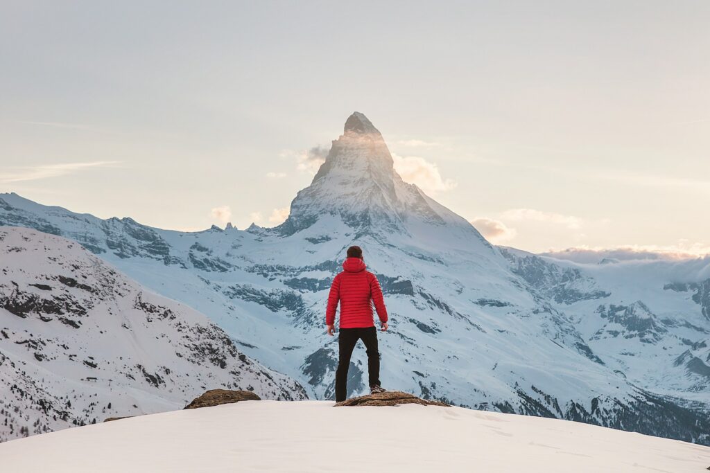 雪山で山頂を見上げる男性