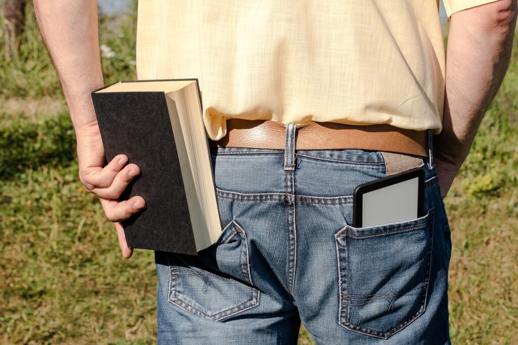 電子書籍リーダーと本をズボンのポケットに入れようとする男性